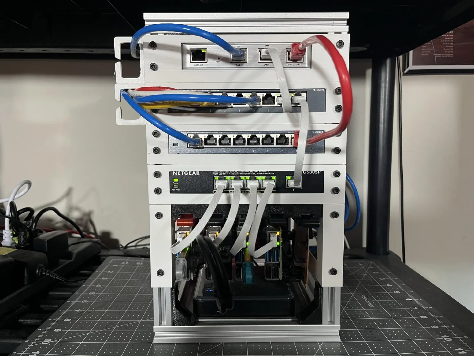 Một homelab nhỏ gọn gồm router, switch và các máy tính nhỏ xếp trên kệ