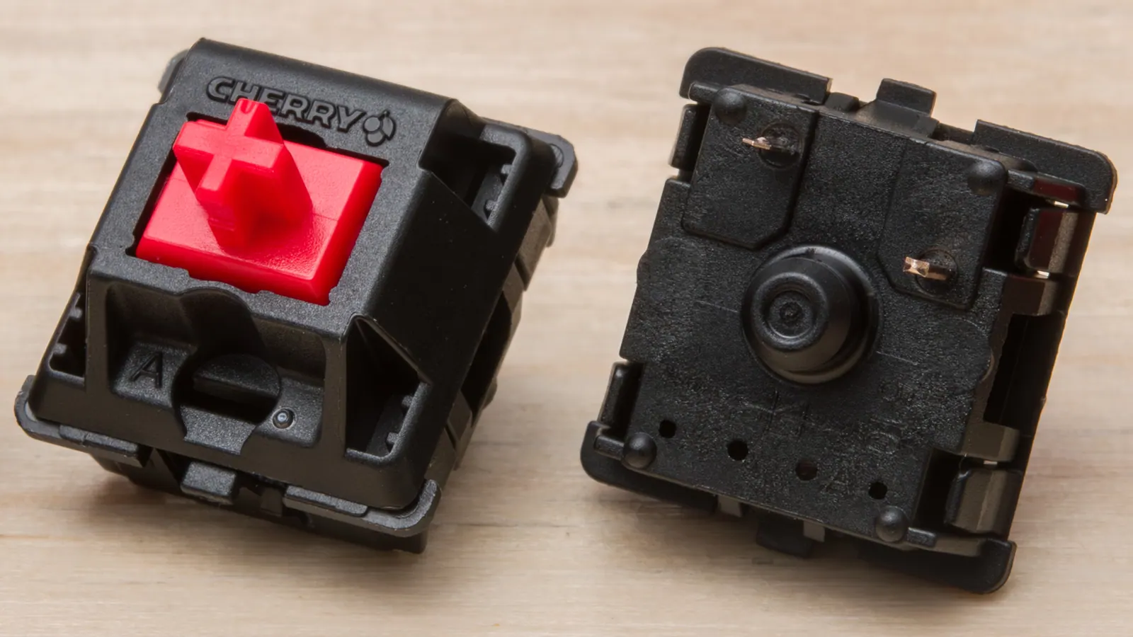 Switch Cherry MX Red nhìn từ trên và từ đáy, thấy rõ stem màu đỏ hình dấu cộng và chân tiếp điểm bằng đồng